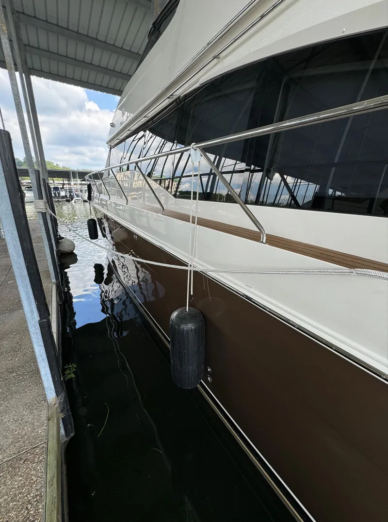 Slide: The Image of 2013 Carver 54 Voyager yacht docked, side view with fenders, under a covered marina. - 4