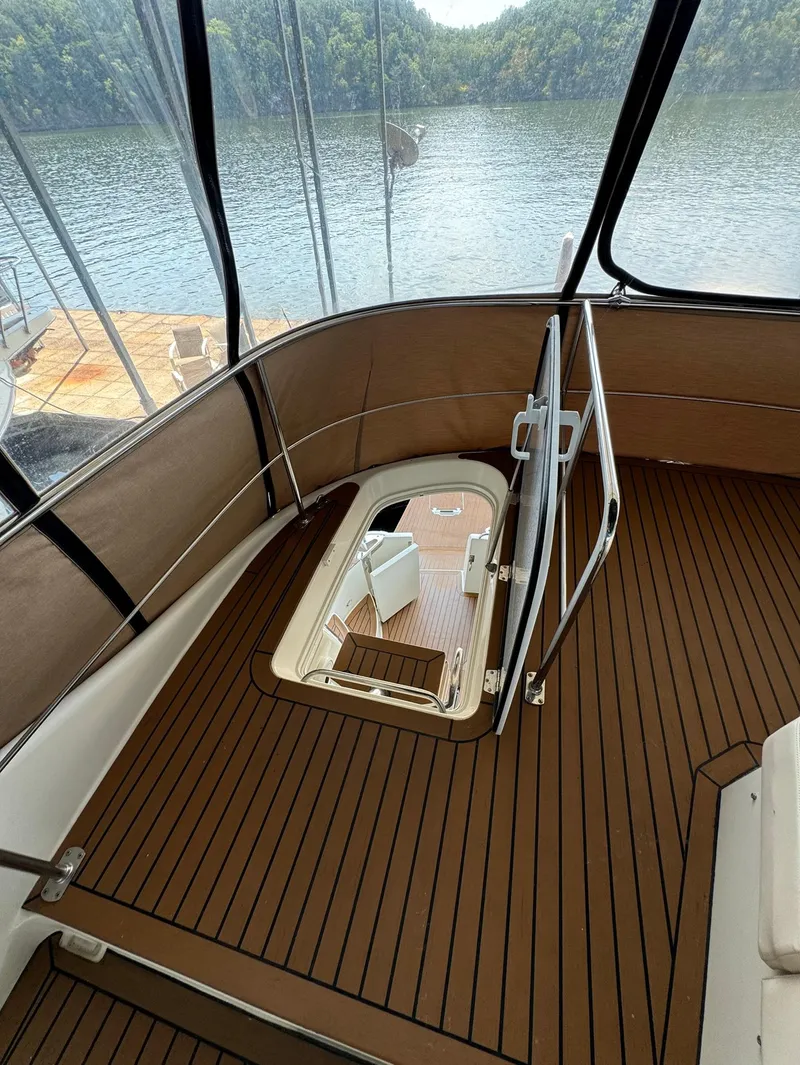 Slide: The Image of 2013 Carver 54 Voyager yacht interior with wood flooring, overlooking serene lake and forest. - 43