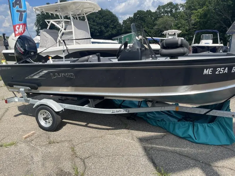 Slide: The Image of 2023 Lund 1600 Fury boat on trailer, parked outdoors under a sunny sky. - 0