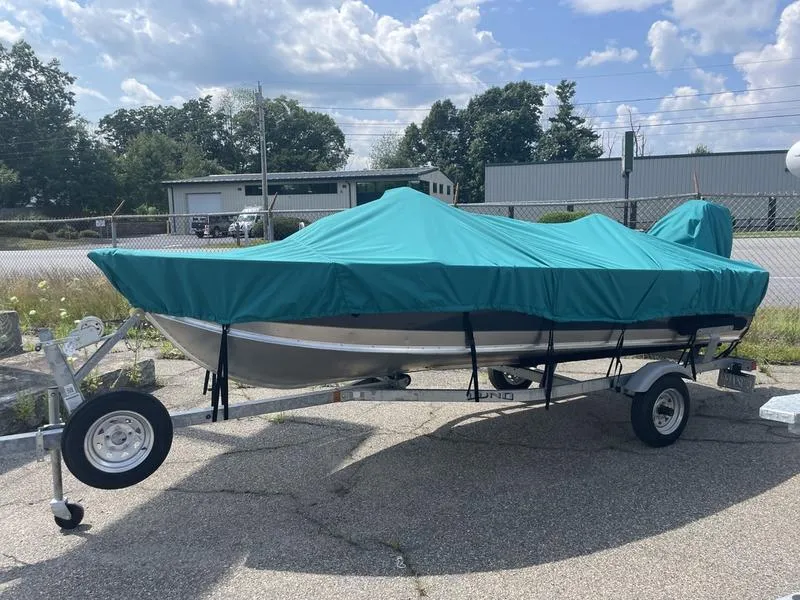 Slide: The Image of 2023 Lund 1600 Fury boat on trailer with teal cover, parked outdoors. - 2