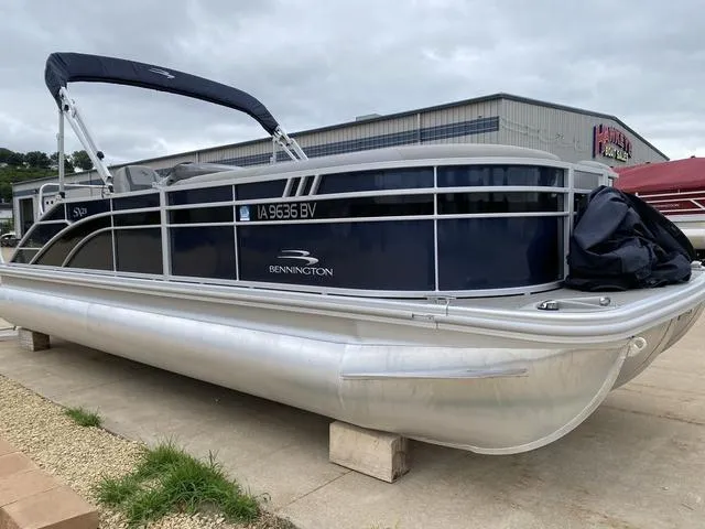 Slide: The Image of 2022 Bennington 22 SSBX pontoon boat with canopy, parked outdoors. - 1