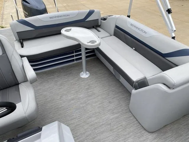 Slide: The Image of 2022 Bennington 22 SSBX pontoon boat interior with gray seating and a small table. - 12