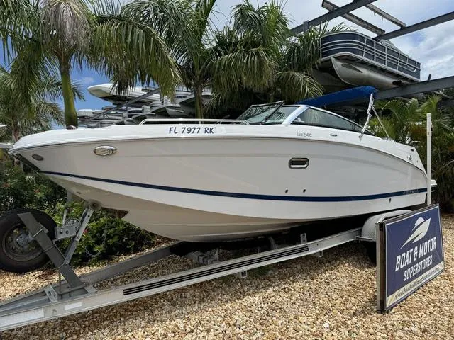 Slide: The Image of 2018 Four Winns HD240 OB boat on trailer, surrounded by palm trees. - 2