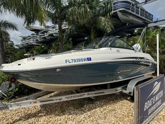 Slide: The Image of 2021 Stingray 201DS boat on trailer, surrounded by palm trees. - 2