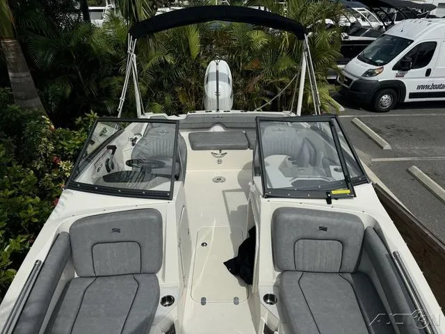 Slide: The Image of 2021 Stingray 201DS boat with gray seating, parked near tropical foliage and a white van. - 20