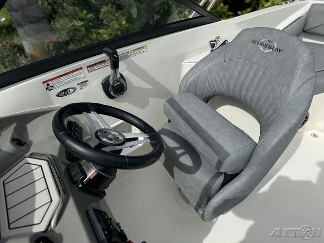 Slide: The Image of 2021 Stingray 201DS boat interior with steering wheel and gray captain's chair. - 21