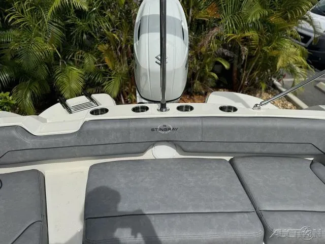 Slide: The Image of 2021 Stingray 201DS boat interior with seating and motor, surrounded by lush greenery. - 24