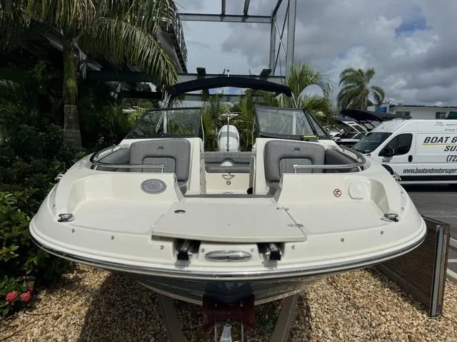 Slide: The Image of 2021 Stingray 201DS boat, front view, parked outdoors with palm trees and a van nearby. - 4