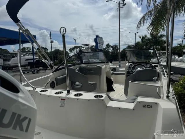 Slide: The Image of 2021 Stingray 201DS boat interior with seating and steering wheel, parked outdoors. - 8