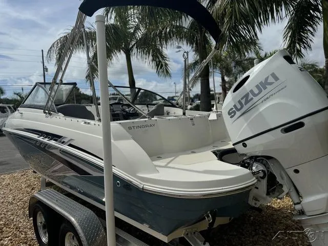 Slide: The Image of 2021 Stingray 201DS boat with Suzuki engine, parked on a trailer under palm trees. - 9