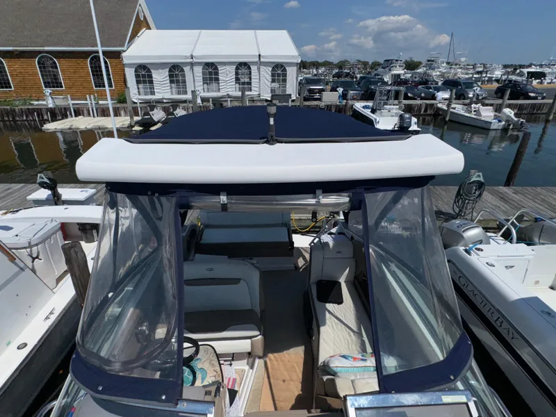 Slide: The Image of 2017 Regal 28 Express boat docked at marina with clear canopy and seating area. - 14