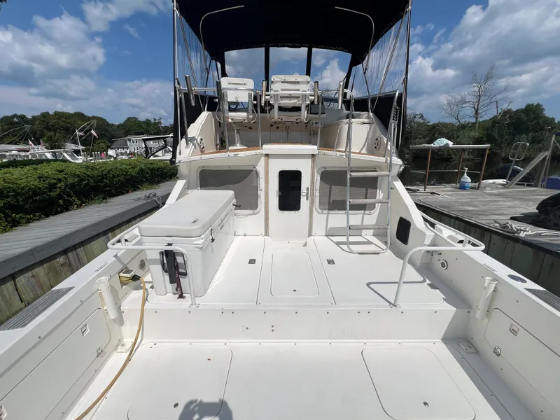 Slide: The Image of 1990 Bertram 28 Flybridge boat with spacious deck and flybridge under a clear sky. - 13