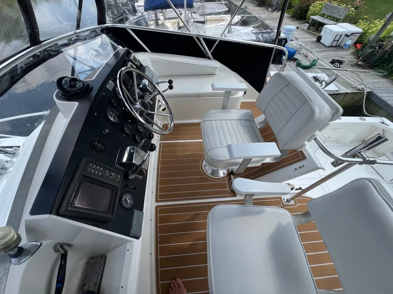 Slide: The Image of 1990 Bertram 28 Flybridge helm with white seating and wooden deck. - 17