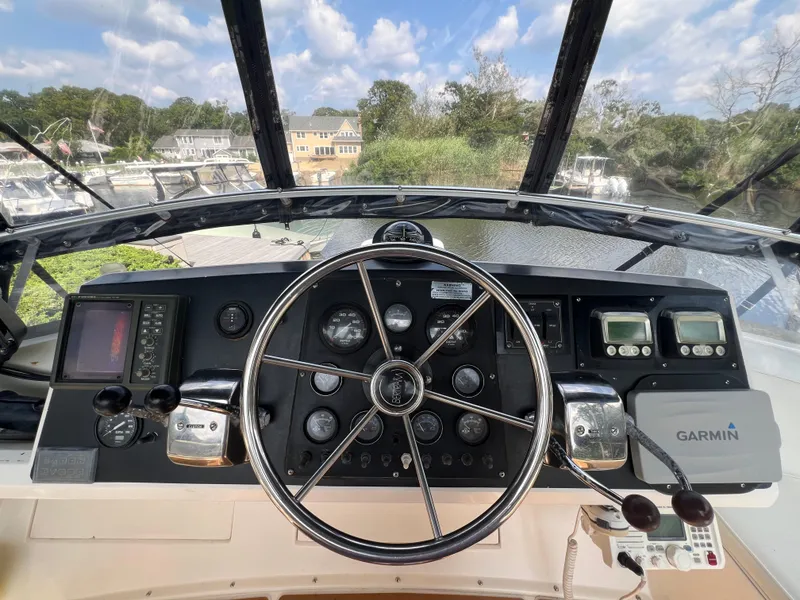 Slide: The Image of 1990 Bertram 28 Flybridge helm with steering wheel, gauges, and Garmin navigation system. - 21