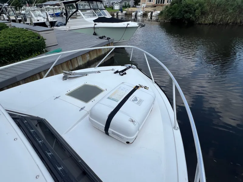 Slide: The Image of 1990 Bertram 28 Flybridge boat docked by a calm waterfront. - 23