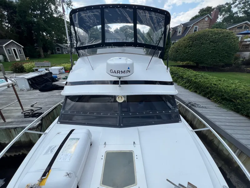 Slide: The Image of 1990 Bertram 28 Flybridge boat docked, featuring Garmin equipment, surrounded by greenery and houses. - 25