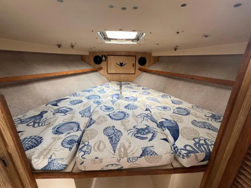 Slide: The Image of 1990 Bertram 28 Flybridge cabin with nautical-themed bedding and wooden accents. - 29