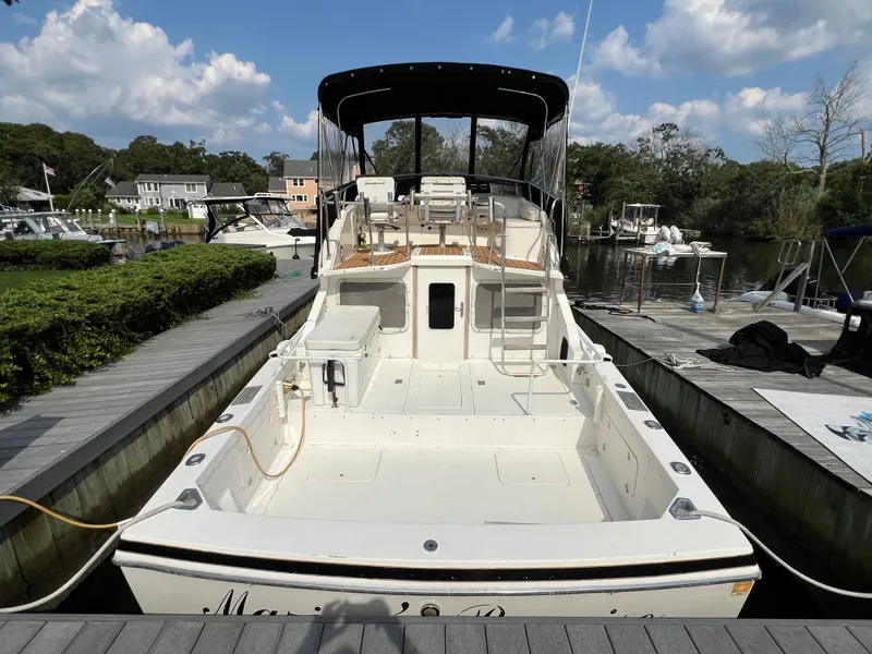 Slide: The Image of 1990 Bertram 28 Flybridge boat docked, featuring spacious deck and flybridge under clear skies. - 4