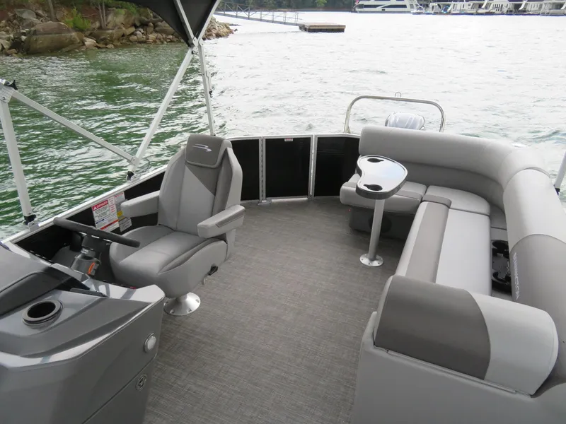 Slide: The Image of 2025 Bennington 20SVL-SPS pontoon boat interior with gray seating and helm on a lake. - 13