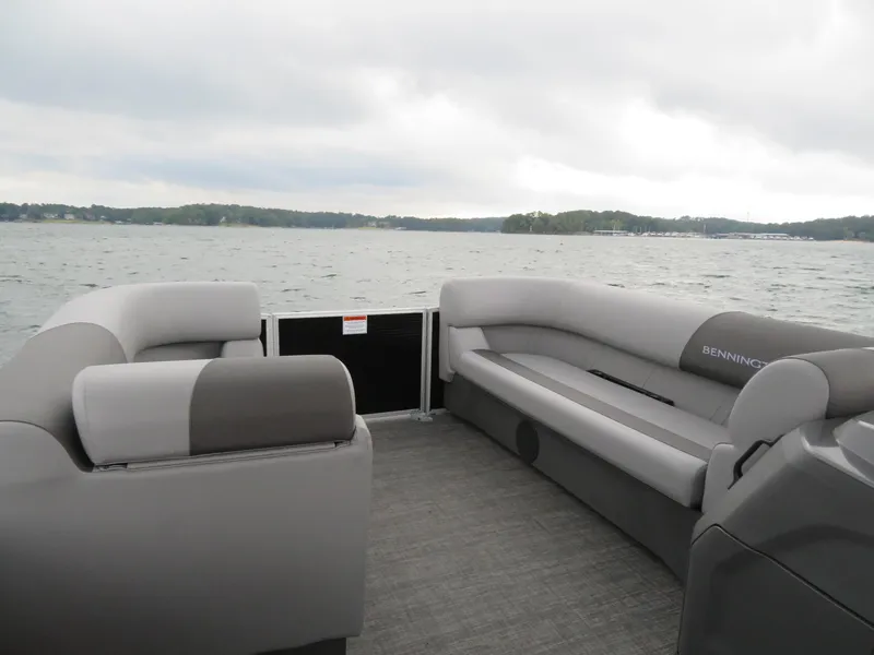 Slide: The Image of 2025 Bennington 20SVL-SPS pontoon boat interior with gray seating on a lake. - 16