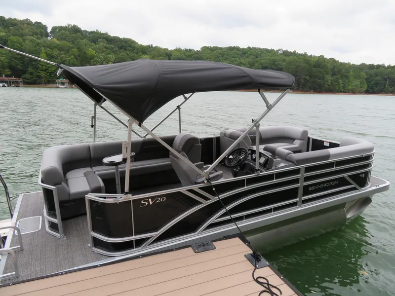 Slide: The Image of 2025 Bennington 20SVL-SPS pontoon boat docked on a lake with lush green trees. - 19