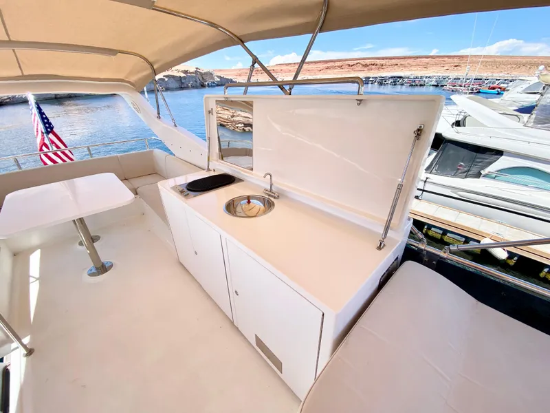 Slide: The Image of 2014 Dyna 52 yacht deck with kitchenette and seating, docked by the water. - 13