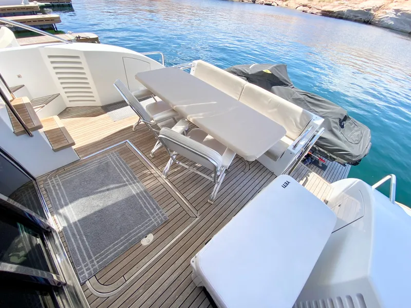 Slide: The Image of Luxurious 2014 Dyna 52 yacht deck with seating and table, overlooking serene blue waters. - 9