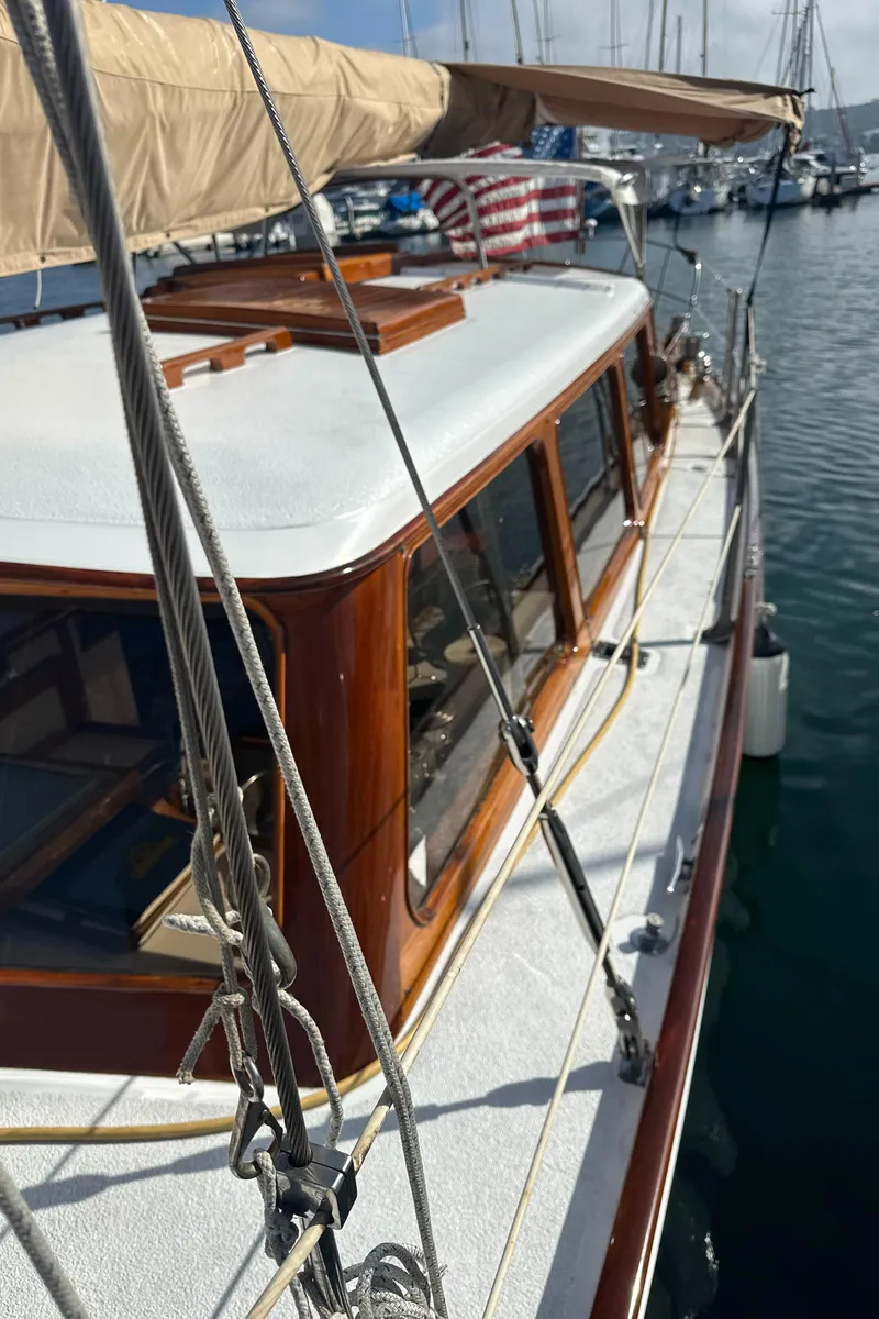 Slide: The Image of 1969 Calkins 50 Pilot House sailboat deck with wooden accents, docked in a marina. - 12