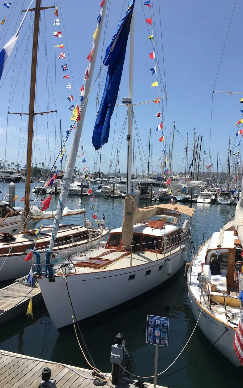 Slide: The Image of 1969 Calkins 50 Pilot House sailboat docked, adorned with colorful flags, in a marina. - 34