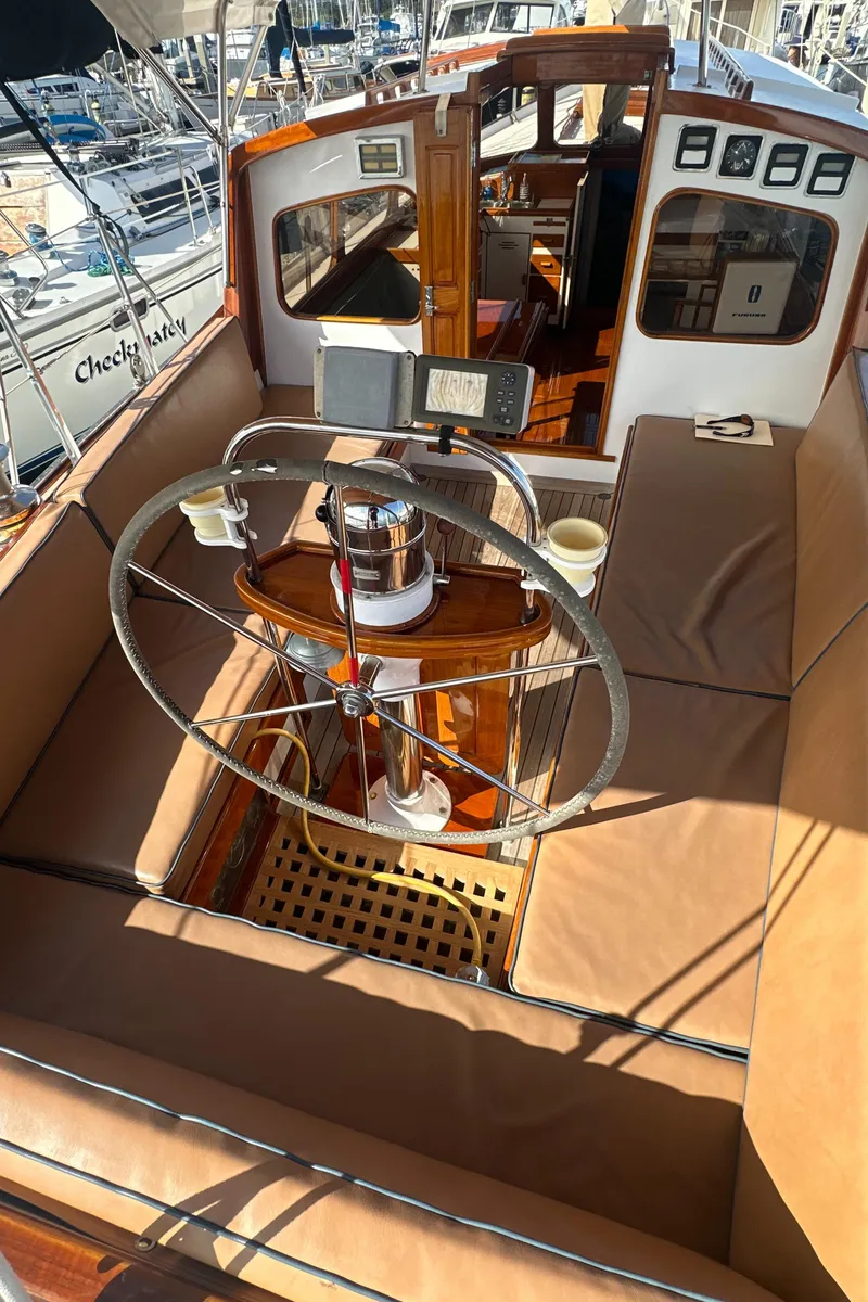 Slide: The Image of 1969 Calkins 50 Pilot House sailboat docked, featuring wooden deck and American flag. - 6