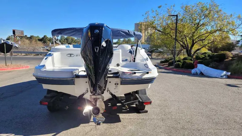 Slide: The Image of 2024 Tahoe 2150 boat with outboard motor, parked outdoors on a sunny day. - 2