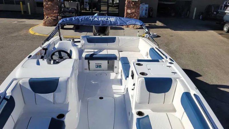 Slide: The Image of 2024 Tahoe 2150 boat interior with blue and white seating, docked outdoors. - 3