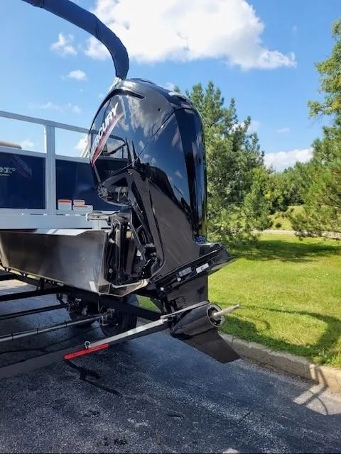 Slide: The Image of 2024 Ranger Reata 200F boat with Mercury outboard motor, parked on a sunny day. - 2