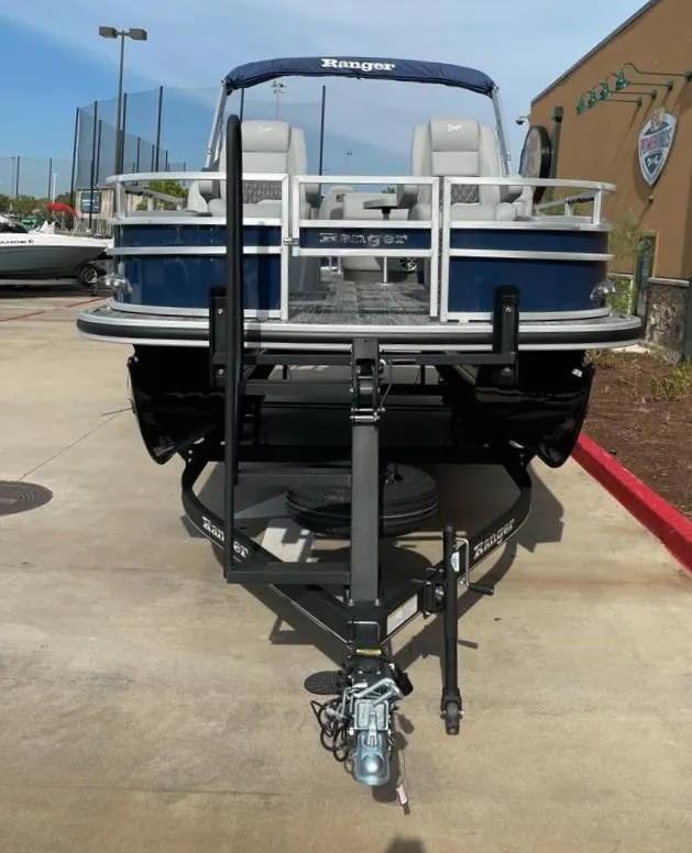 Slide: The Image of 2024 Ranger Reata 220F pontoon boat on trailer, parked outdoors. - 1