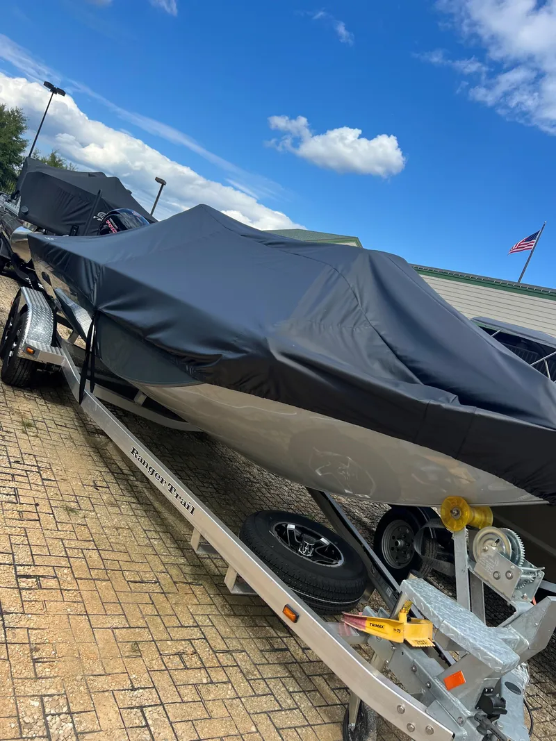 Slide: The Image of 2024 Ranger RB200 boat covered on trailer, parked outdoors under blue sky. - 5