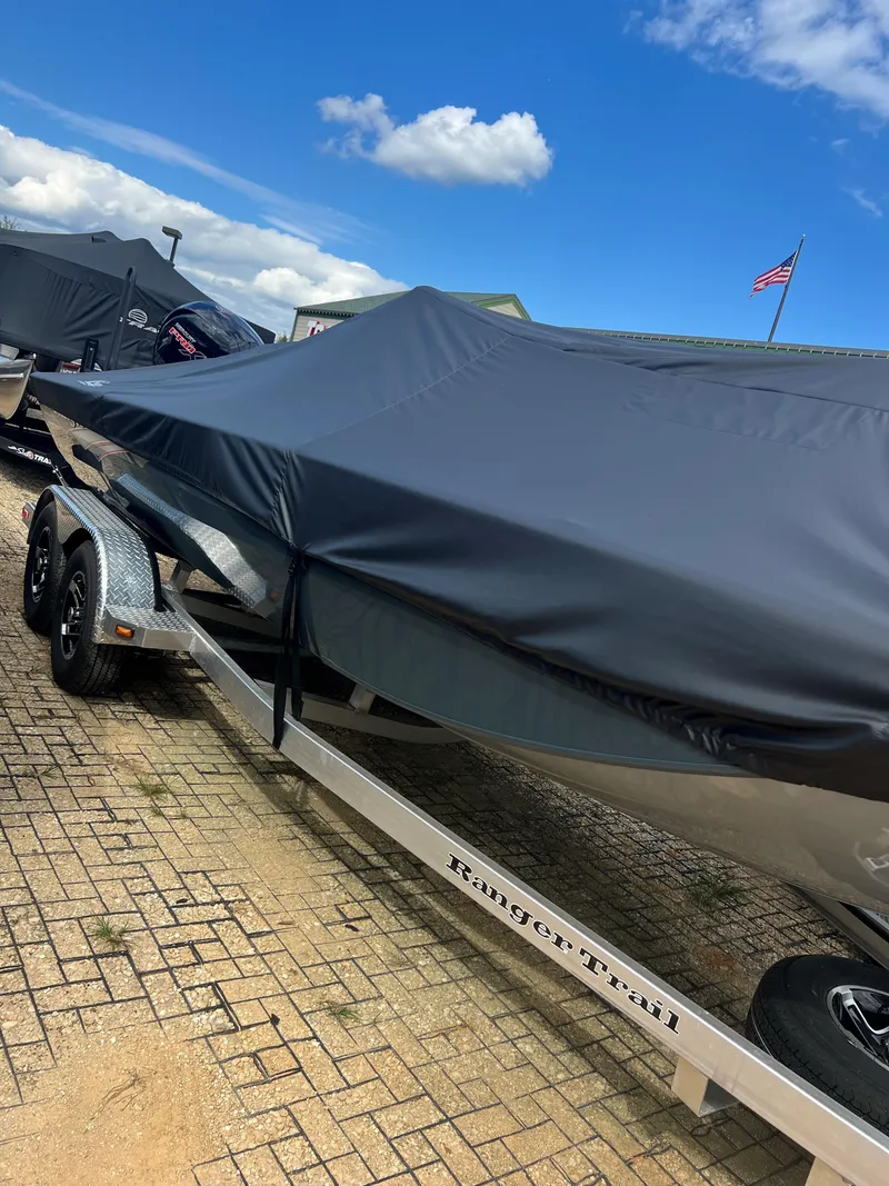 Slide: The Image of 2024 Ranger RB200 boat covered on a trailer, parked on a brick surface under a blue sky. - 8
