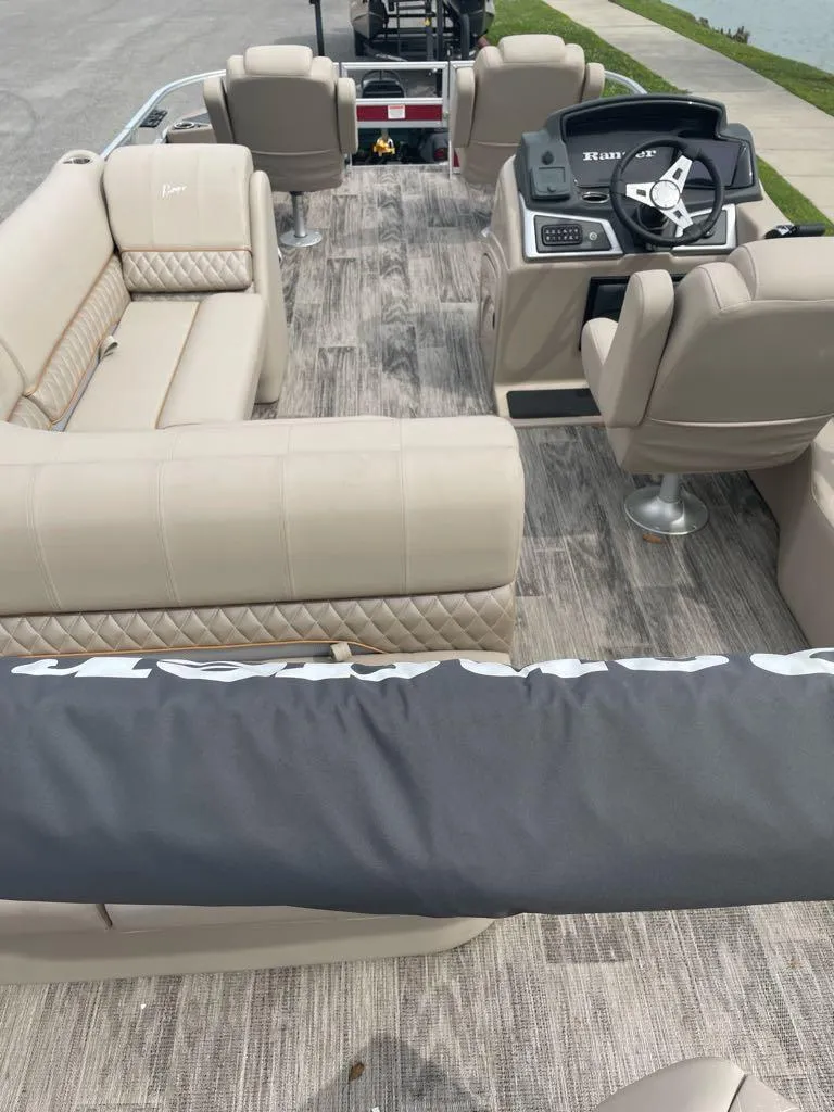 Slide: The Image of 2024 Ranger Reata 220F pontoon boat interior with beige seating and modern helm. - 3
