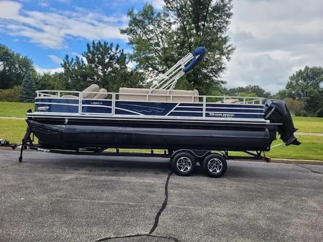 The Image of 2024 Ranger Reata 223F pontoon boat on trailer, parked outdoors. - 0