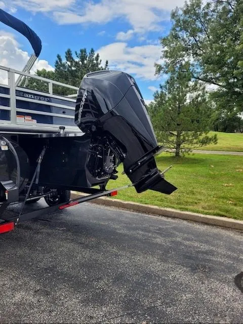 Slide: The Image of 2024 Ranger Reata 223F boat with powerful outboard motor, parked on a scenic road. - 2