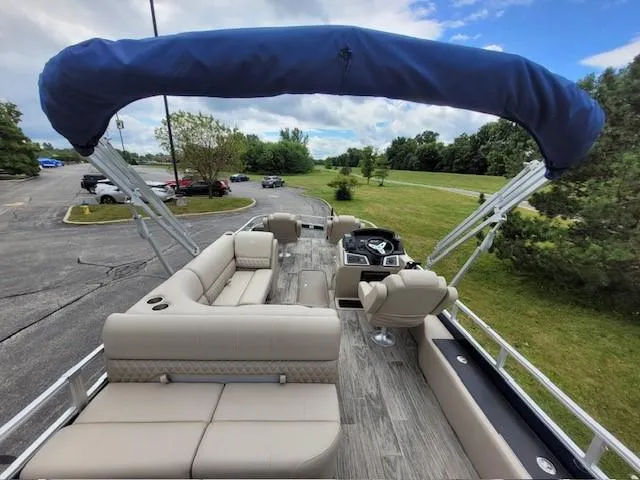 Slide: The Image of 2024 Ranger Reata 223F pontoon boat with spacious seating and canopy, parked outdoors. - 4