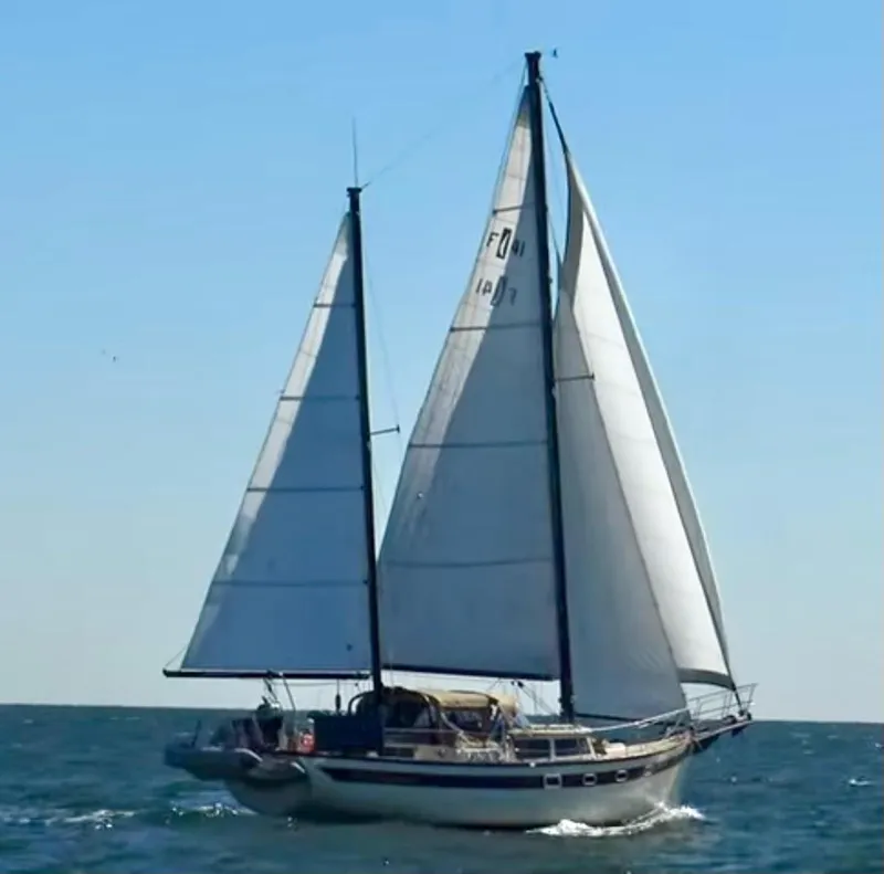 Slide: The Image of 1978 Islander Freeport 41 Ketch sailing on open sea under clear blue sky. - 0