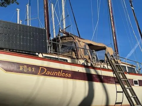 Slide: The Image of 1978 Islander Freeport 41 Ketch sailboat, named "Dauntless," docked under clear blue sky. - 10