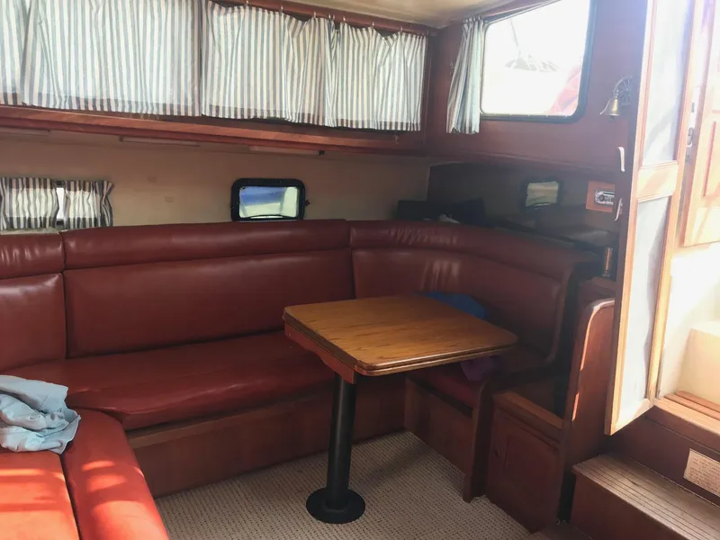 Slide: The Image of 1978 Islander Freeport 41 Ketch interior with red leather seating and wooden table. - 13