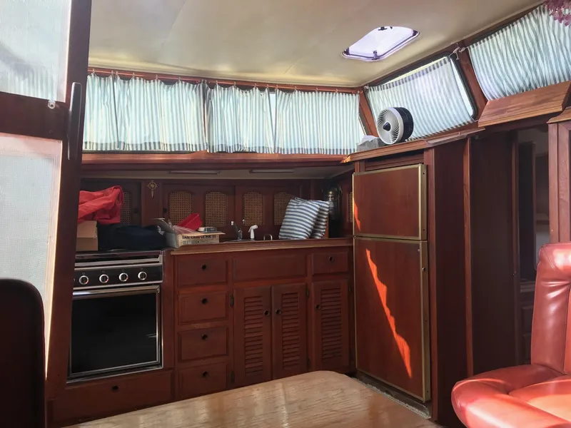 Slide: The Image of 1978 Islander Freeport 41 Ketch interior with wood cabinetry and striped curtains. - 15
