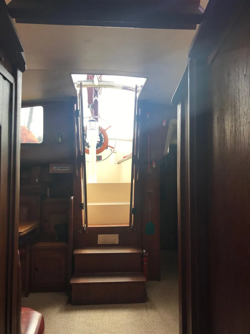 Slide: The Image of Interior view of 1978 Islander Freeport 41 Ketch sailboat, featuring wooden cabinetry and steps. - 16