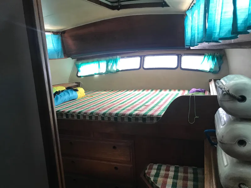 Slide: The Image of Cozy cabin interior of 1978 Islander Freeport 41 Ketch with striped bedding and teal curtains. - 17
