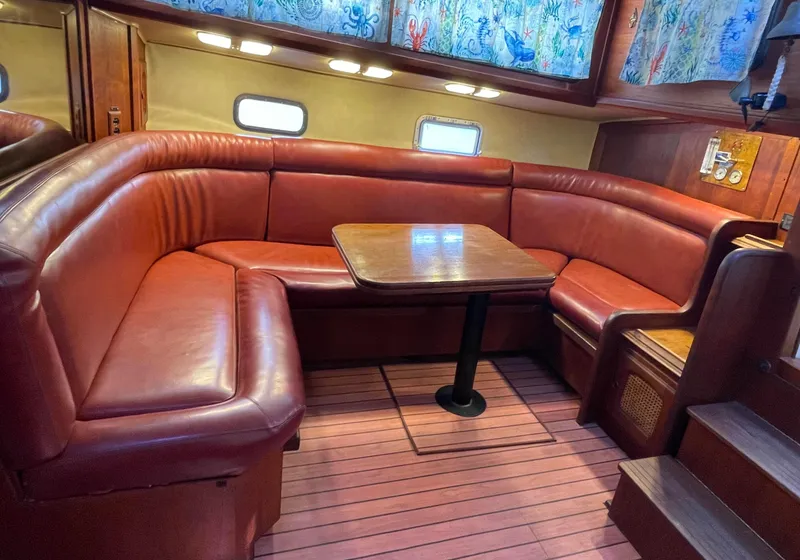Slide: The Image of 1978 Islander Freeport 41 Ketch interior with red leather seating and wooden table. - 21
