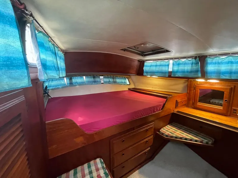 Slide: The Image of 1978 Islander Freeport 41 Ketch cabin with pink bedding and blue curtains. - 22