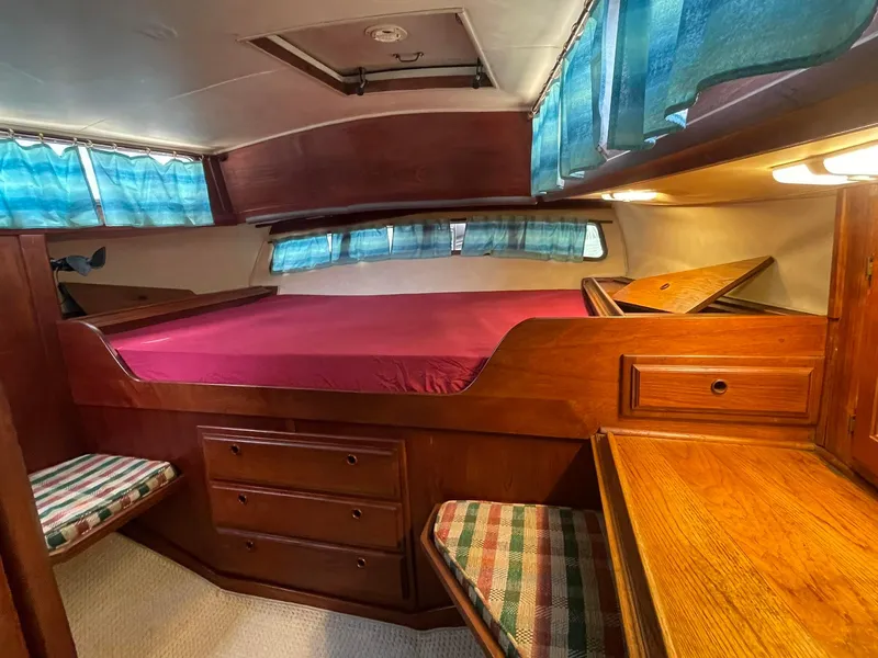 Slide: The Image of 1978 Islander Freeport 41 Ketch cabin with wood interior and blue curtains. - 25