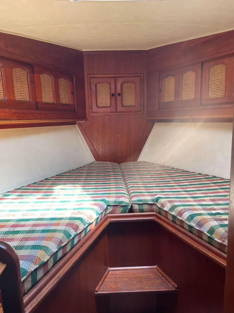 Slide: The Image of 1978 Islander Freeport 41 Ketch cabin with striped bedding and wooden cabinetry. - 26